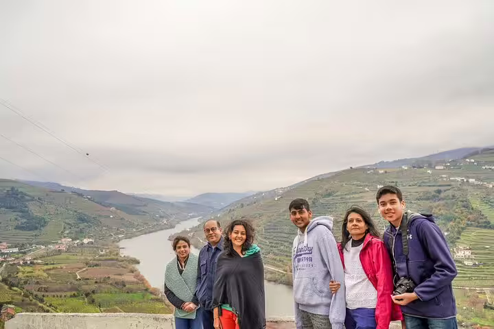Group enjoying a scenic view of Douro Valley vineyards with a river backdrop during a private tour from Lisbon.