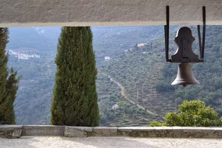 Scenic view of Douro Valley vineyards framed by trees and a bell, highlighting the region's natural beauty.