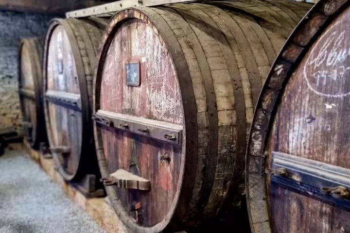 Row of rustic wooden wine barrels in a Douro Valley vineyard, showcasing traditional aging methods.