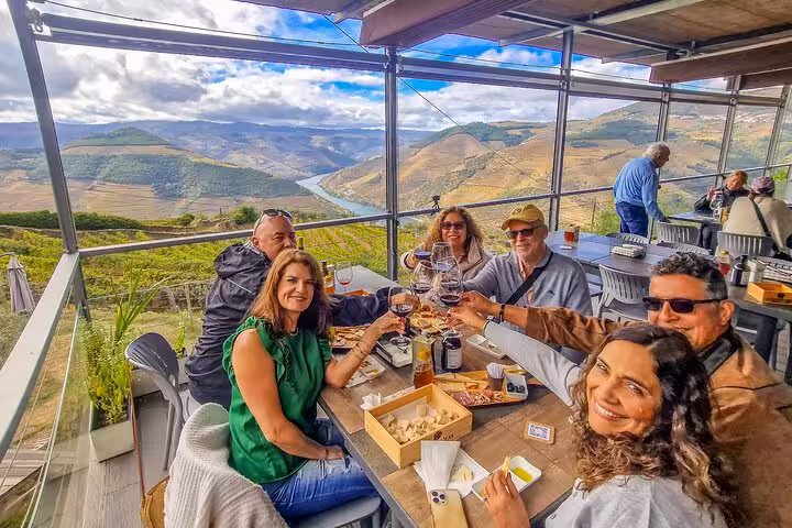 Friends toast Douro Valley wines at a vineyard terrace brunch on a private Porto to Lisbon day tour
