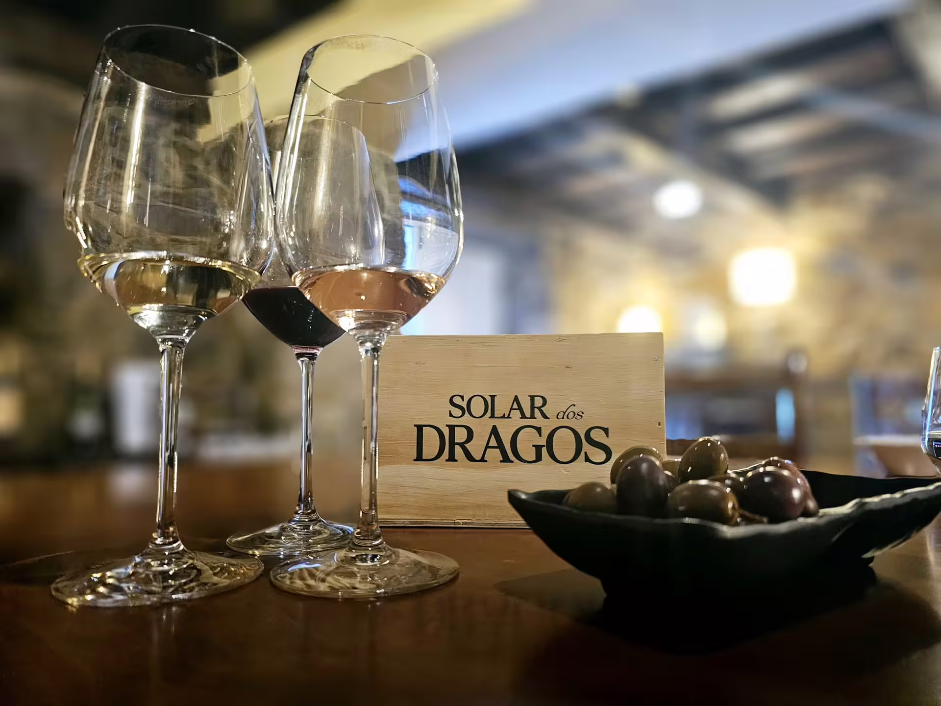 Wine glasses with red, white, and rosé wines on a tasting table in Douro Valley, accompanied by fresh olives.