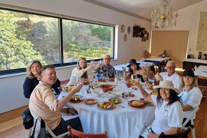 Group enjoying Portuguese lunch and Douro Valley wine tastings indoors, raising glasses on guided tour