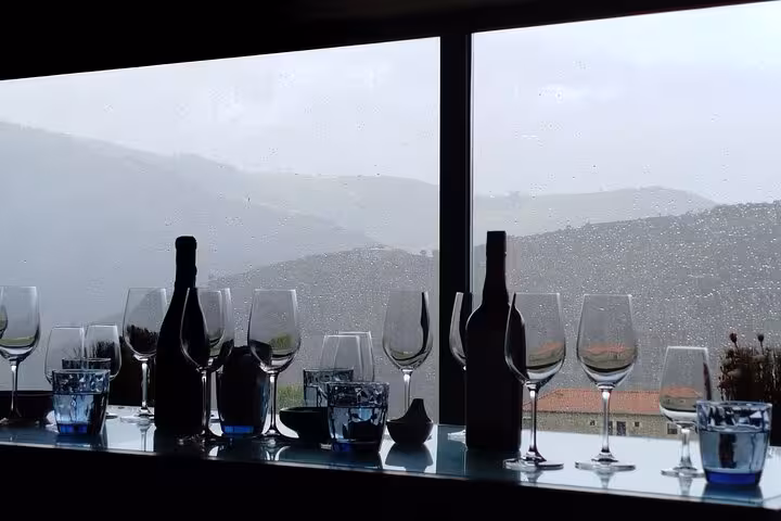 Wine glasses and bottles by a window overlooking Douro Valley hills, ideal for private luxury wine tour tasting