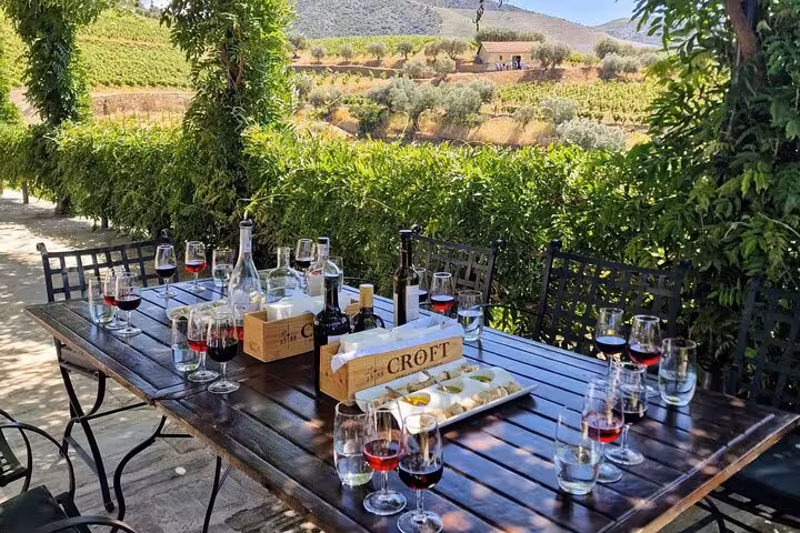 Douro Valley private wine tasting lunch setup on vineyard terrace with Port bottles and glasses in Portugal