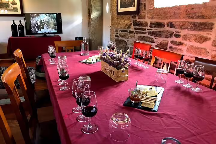 Elegant wine tasting setup in Douro Valley featuring glasses of red wine, cheese platter, and rustic stone walls.