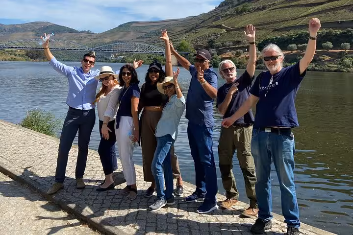 Happy group by Douro River on expert-guided tour with boat cruise, vineyard views, lunch and wine tastings