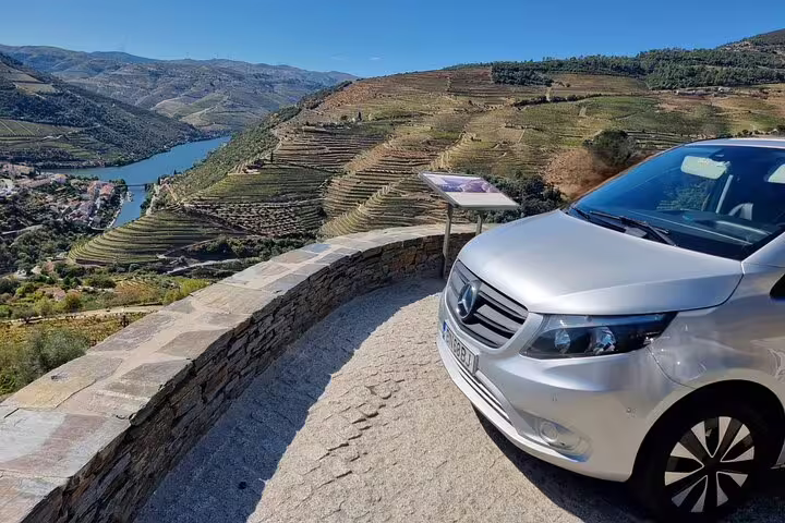 Luxury vehicle parked with panoramic view of Douro Valley vineyards, ideal for private wine tour and exploration.