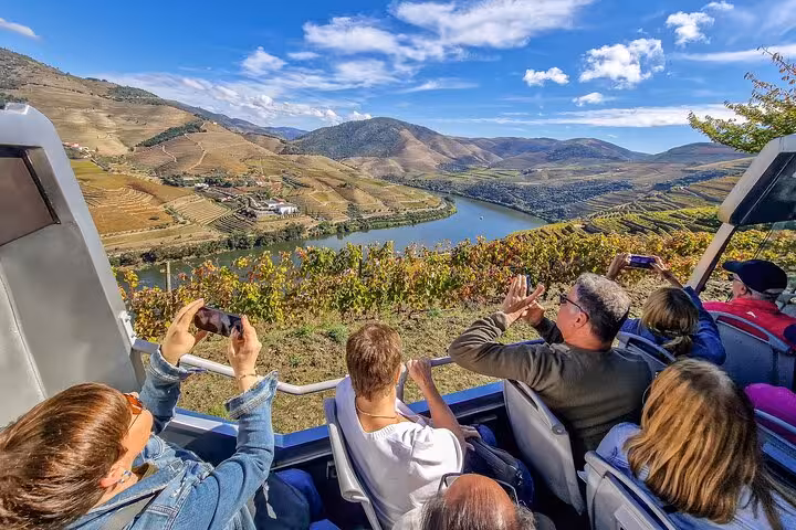 Travelers on a scenic Douro Valley drive stop, photographing river views on the Porto to Lisbon wine tour