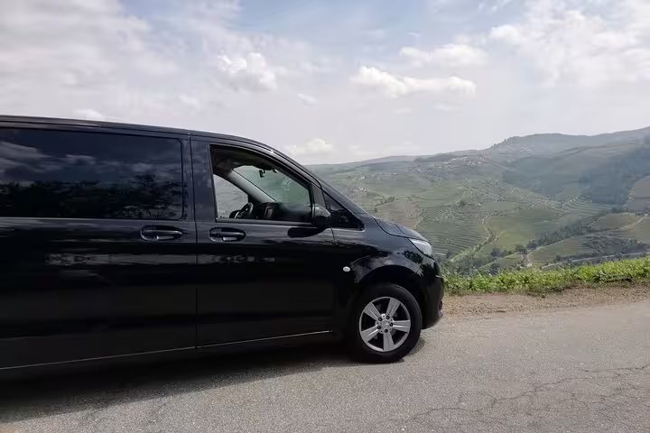 Black van with scenic Douro Valley vineyards in the background on a sunny day.