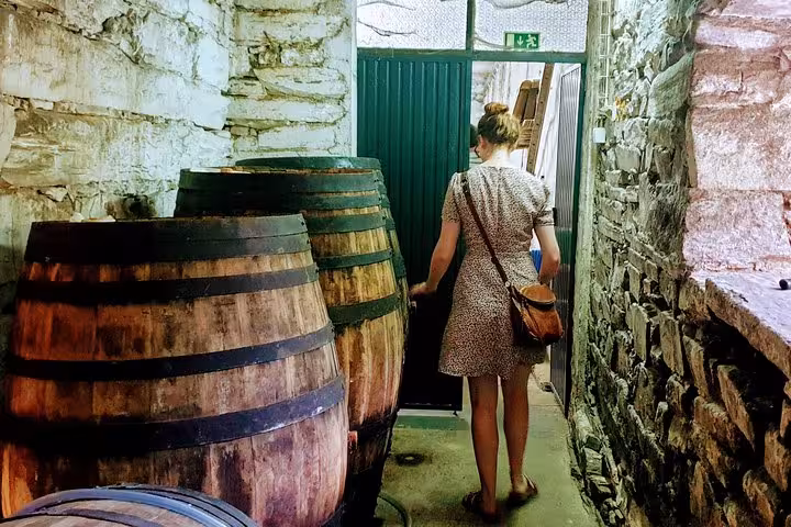Traveler walks past oak barrels in a Douro Valley winery cellar during private guided wine tasting experience