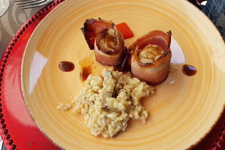 Gourmet dish with bacon-wrapped delicacies and creamy risotto, served at a Douro Valley winery lunch.
