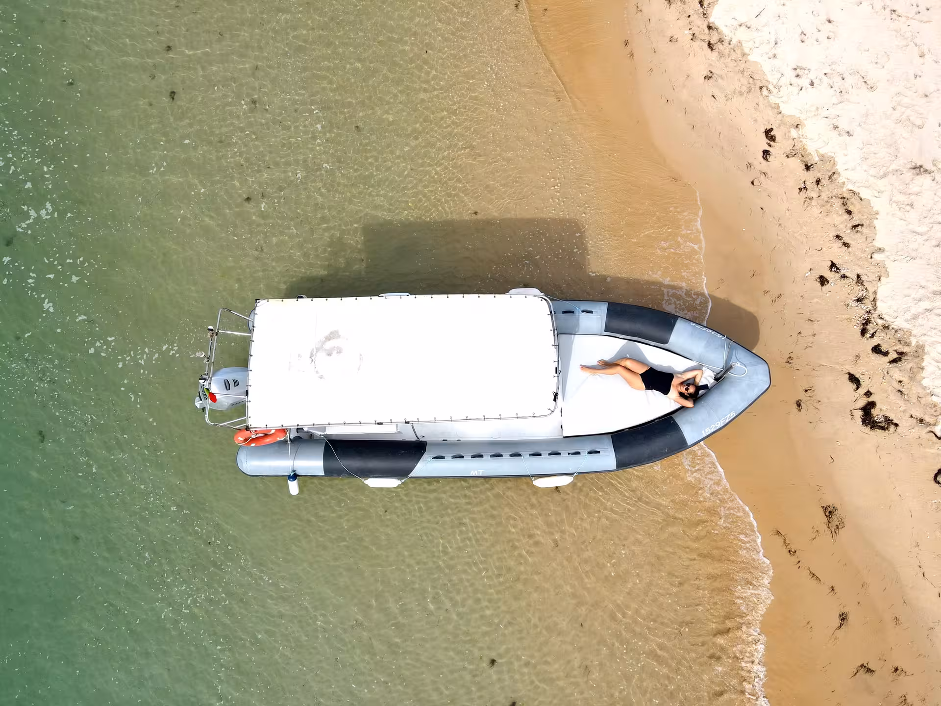 Aerial view of Duarry speed boat rental beached on golden sand, perfect for private coastal cruise tours