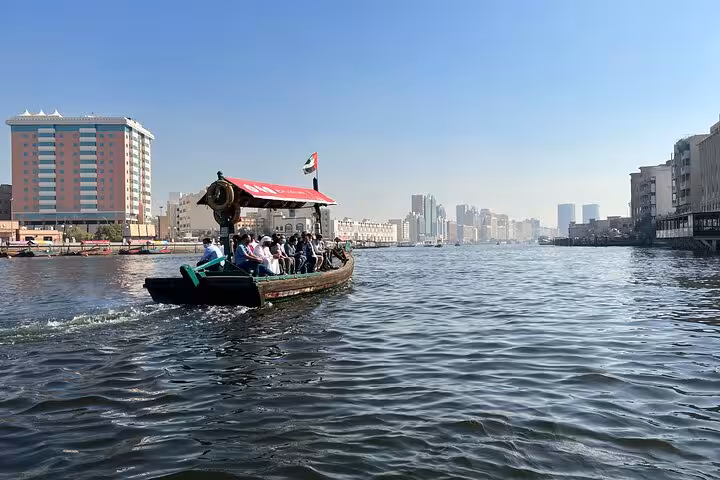 Traditional abra crossing Dubai Creek with skyline views, part of Dubai historical and modern half-day city tour