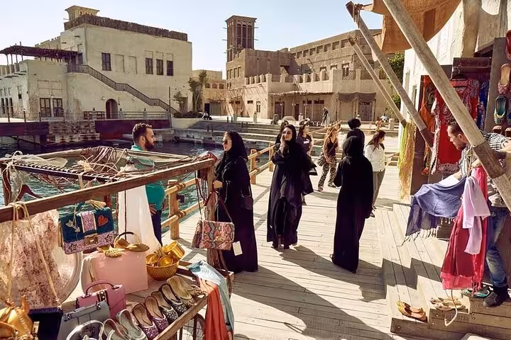 Al Seef waterfront market scene with shoppers browsing stalls, ideal for customizable Dubai souk tour