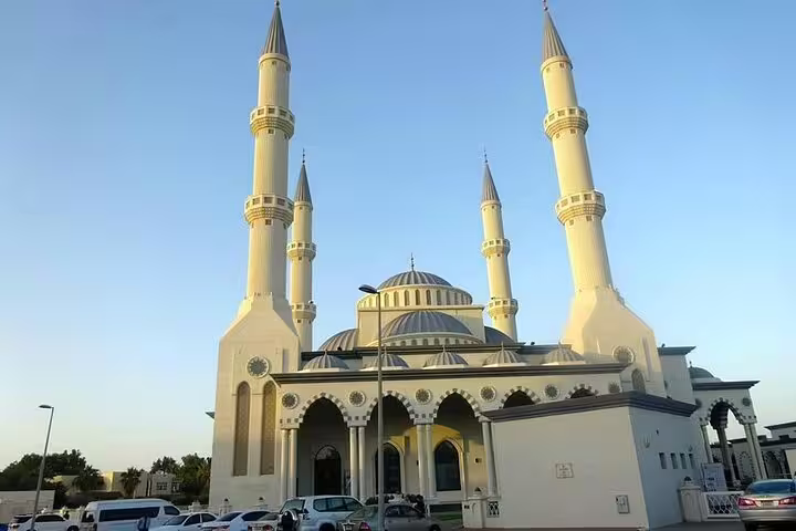 Stunning view of Dubai's Blue Mosque with its elegant minarets against a clear blue sky, featured in a private tour.