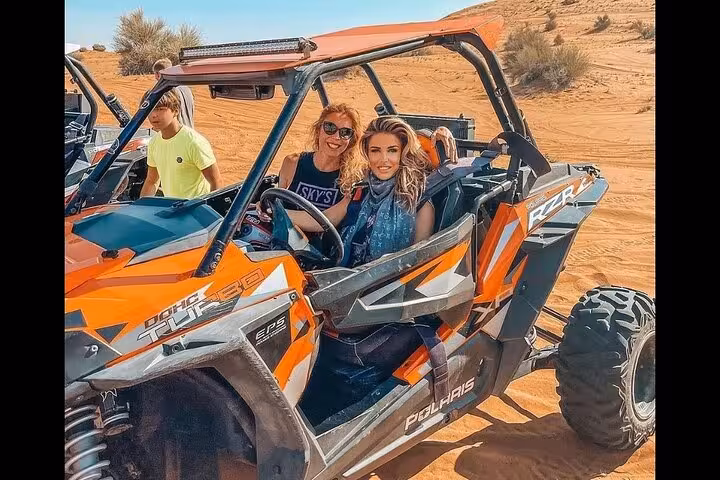 Guests riding a Polaris dune buggy in Dubai desert, thrilling add-on activity on an evening desert safari