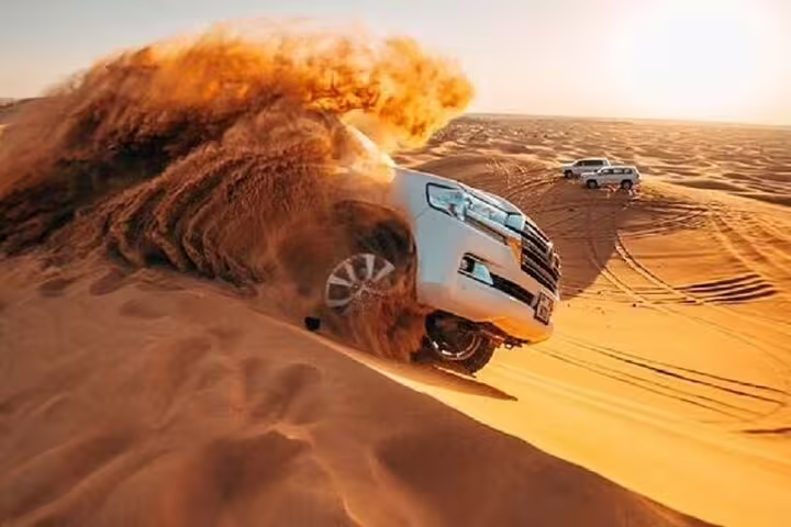 Powerful 4x4 vehicle dune bashing in the Dubai desert, capturing the excitement of a morning safari adventure.