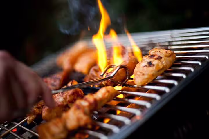 Grilled meats sizzling over open flames during Dubai desert safari BBQ dinner experience.