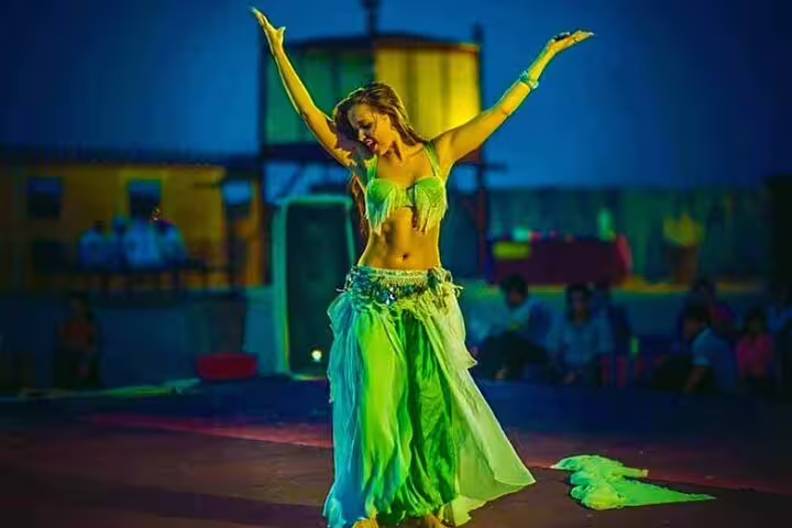 Belly dancer in vibrant costume performing at Dubai desert safari night event.