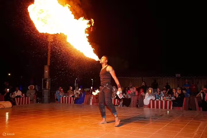 Fire performer captivating the audience with a fiery display during a Dubai desert safari night show.
