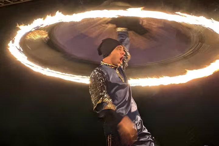 Fiery performer spinning a ring of fire at Dubai desert safari evening show.