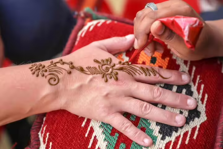 Intricate henna design being applied on a hand, highlighting cultural artistry on a Dubai desert safari.