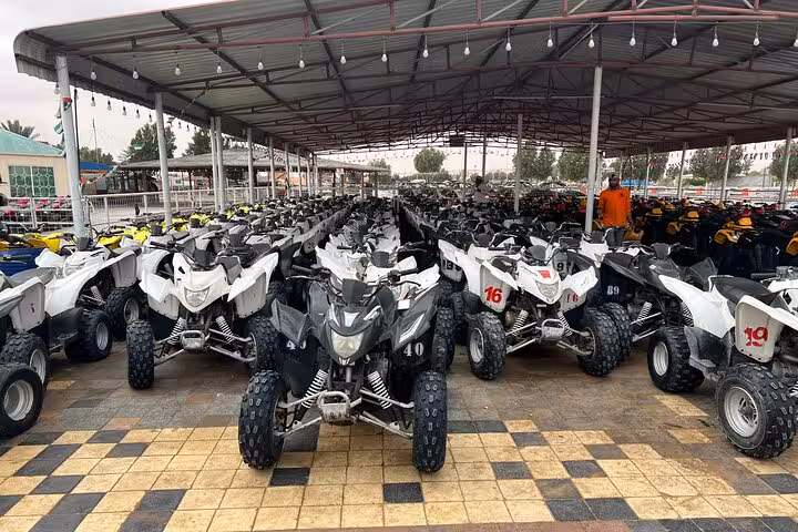 Quad bikes lined up at Dubai desert safari camp for ATV ride, sandboarding, BBQ dinner and fire show
