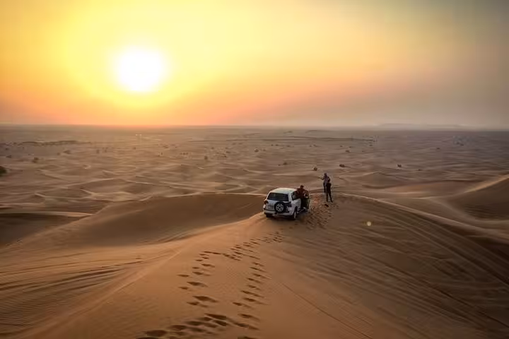 Sunrise 4x4 stop on Dubai morning desert safari, golden dunes and footprints with panoramic views