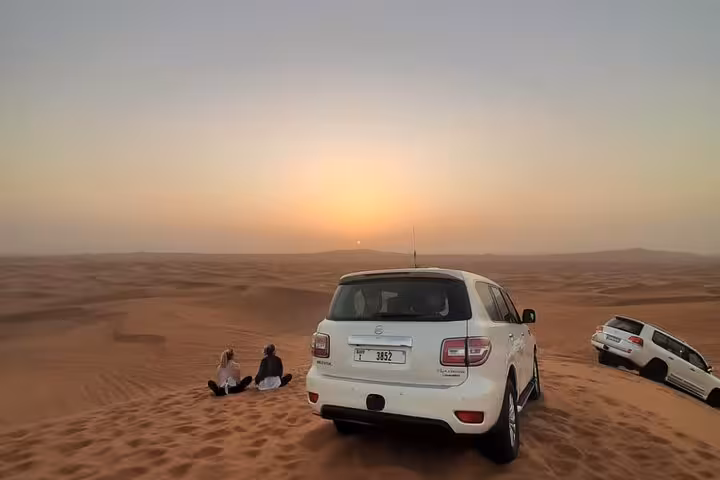 Dubai desert safari sunset photo with 4x4 dune bashing stop on red dunes, perfect evening tour moment