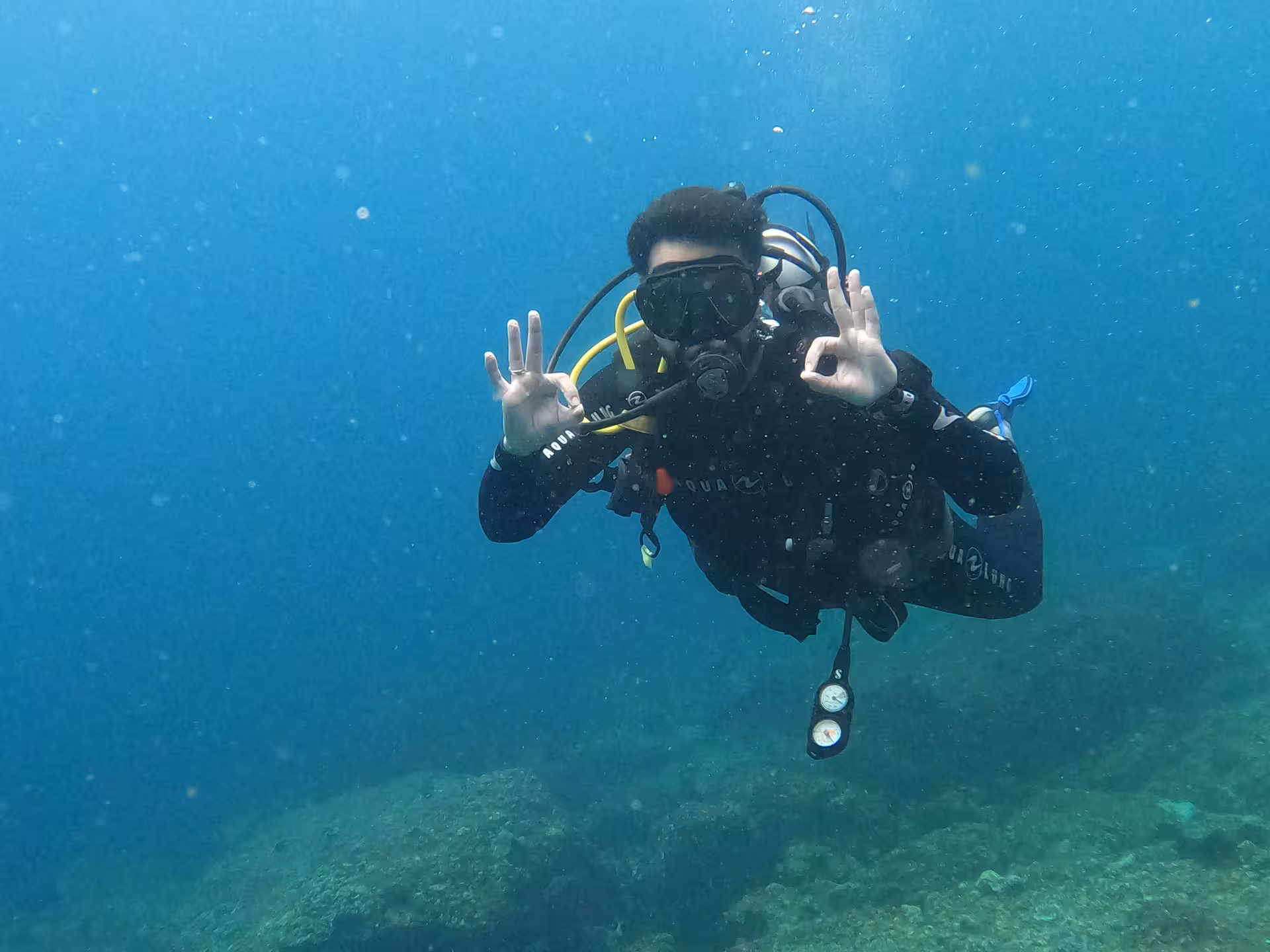 A scuba diver gives an OK signal underwater during a dive in Fujairah, part of the Dubai to Fujairah diving experience.