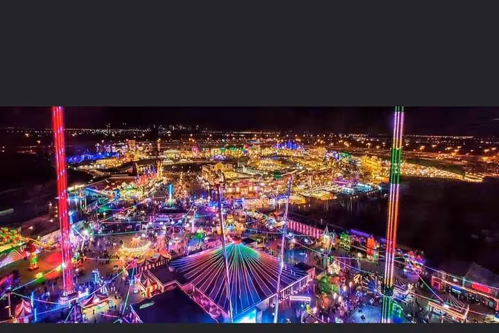 Aerial night view of Dubai Global Village glowing with colorful lights on private tour with hotel pickup