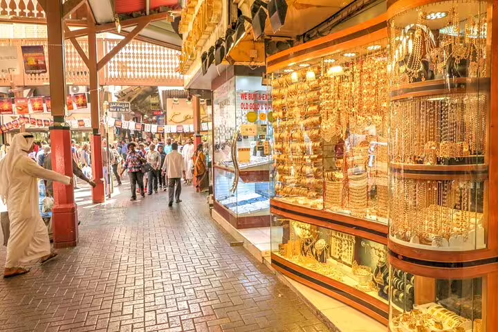 Bustling Dubai Gold Souk with shoppers exploring vibrant jewelry displays on a sunny day.