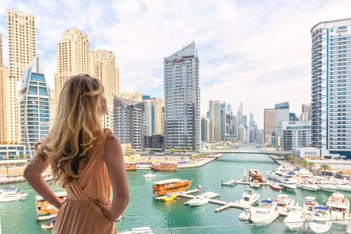 Woman admiring the modern skyscrapers and yachts in Dubai Marina, a highlight of the full-day private tour.