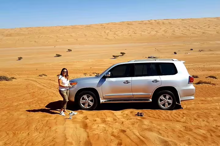 SUV parked on golden desert sands during Dubai to Muscat private transfer tour, highlighting adventure travel.