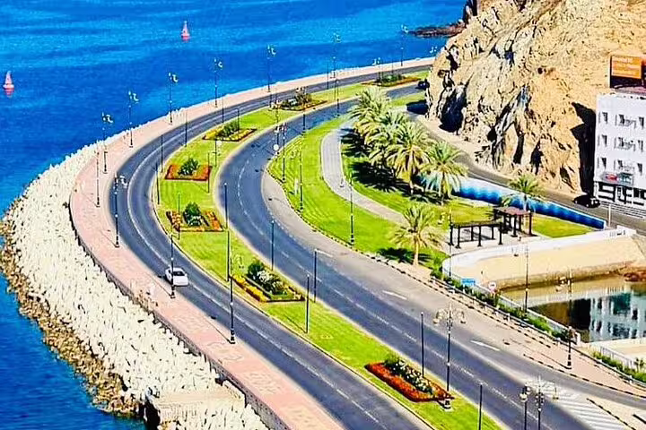Coastal road in Muscat with palm trees and ocean views, ideal for a scenic private transfer from Dubai.
