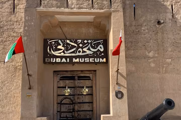 Entrance to Dubai Museum at Al Fahidi Fort with UAE flags, key stop on Dubai historical city tour