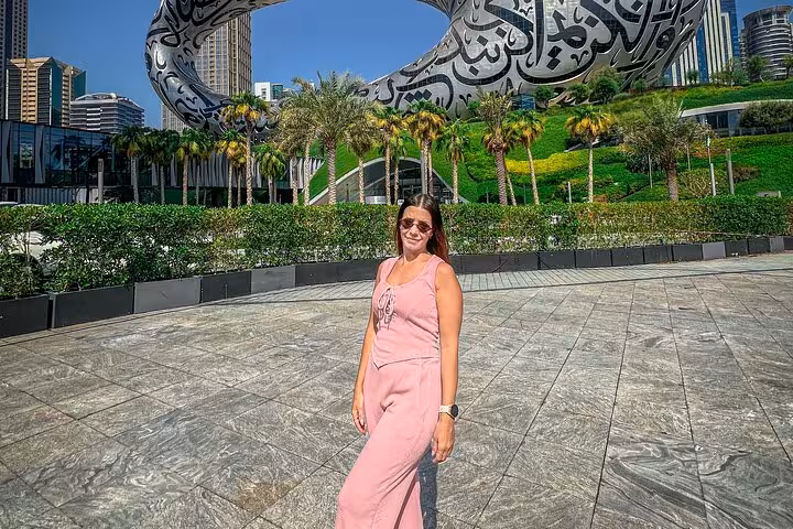 Woman in pink jumpsuit poses by Dubai Museum of the Future, highlighting a Dubai Layover Instagram Private Videography Tour.
