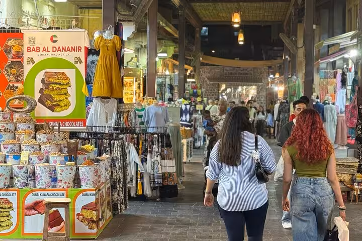 Dubai city tour stop at Old Souk market with shoppers, textiles and souvenir stalls in Deira