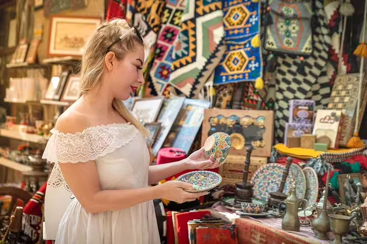 Traveler browsing traditional handicrafts and ceramics in Dubai Old Town souk during guided walking tour with local snack stops