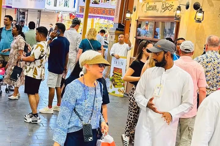 Tour guide explaining Dubai souk streets to visitors, part of Dubai city tour from Ras Al Khaimah with kids free