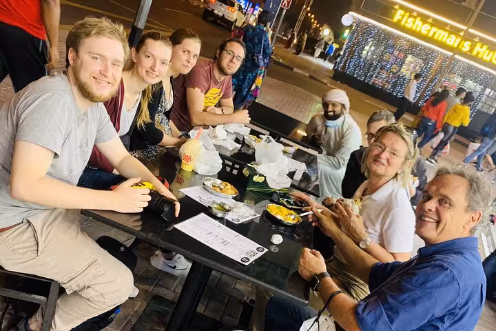 Tour guests enjoying Dubai street food tastings on an Old Dubai walking tour with local guide at night