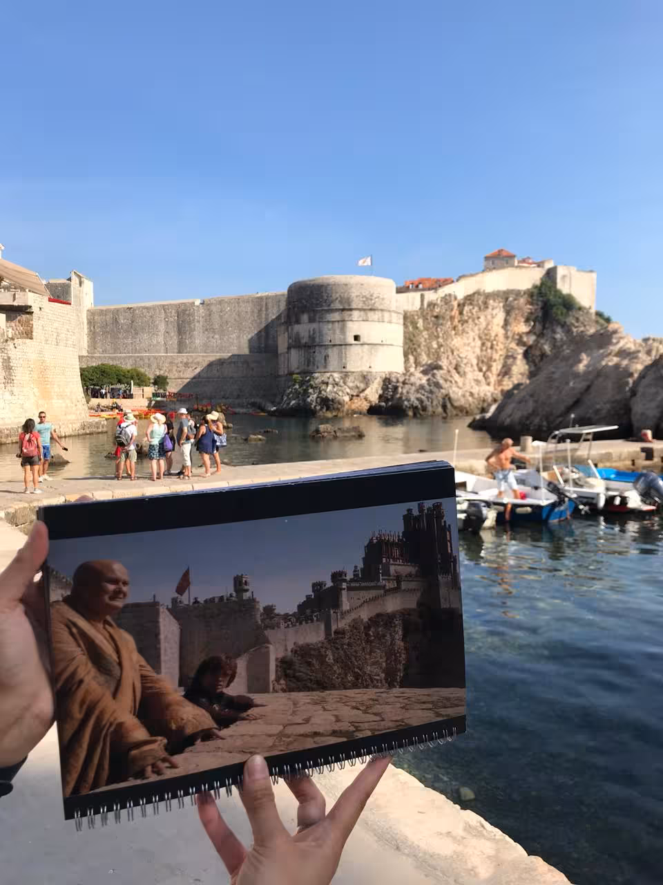 Guide holds Game of Thrones scene overlay at Dubrovnik harbor, Fort Lovrijenac on combo history tour