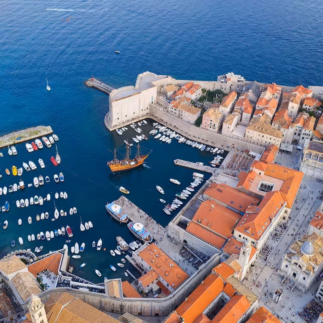 Aerial view of Dubrovnik Old Town port, city walls and boats on Adriatic Sea, scenic history city tour