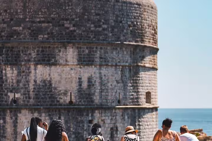 Travelers admiring Dubrovnik Old Town fort tower by the Adriatic Sea on a private guided walking tour