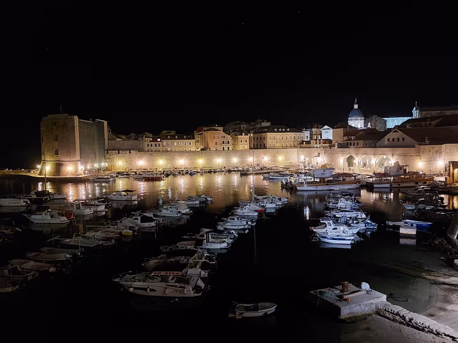 Dubrovnik Old Town harbor at night with boats and illuminated walls on the sunset boat & history tour