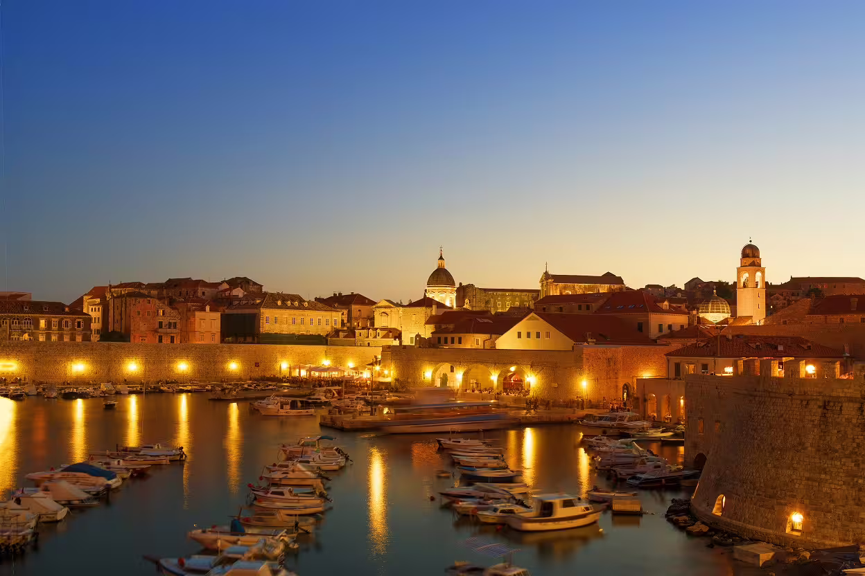 Dubrovnik Old Town harbor at sunset with boats and city walls, Croatia UNESCO heritage self-drive tour