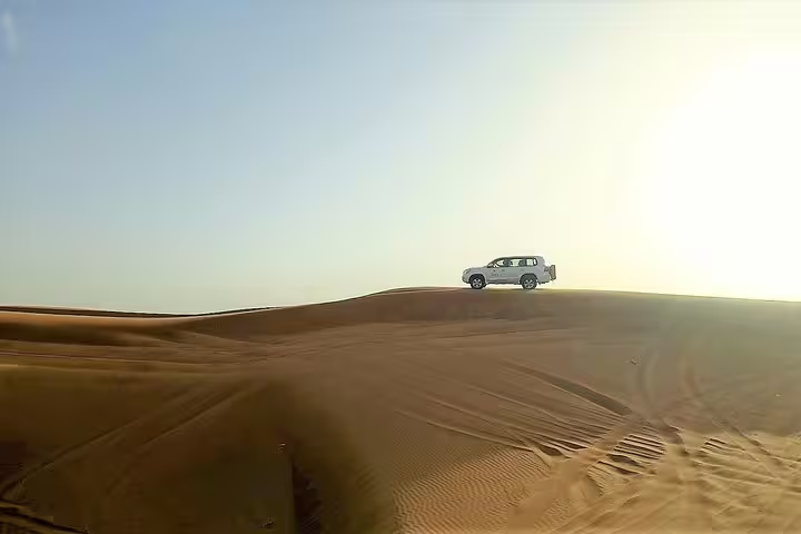 4x4 vehicle navigating the golden dunes under a clear sky during an exhilarating dune bashing adventure.