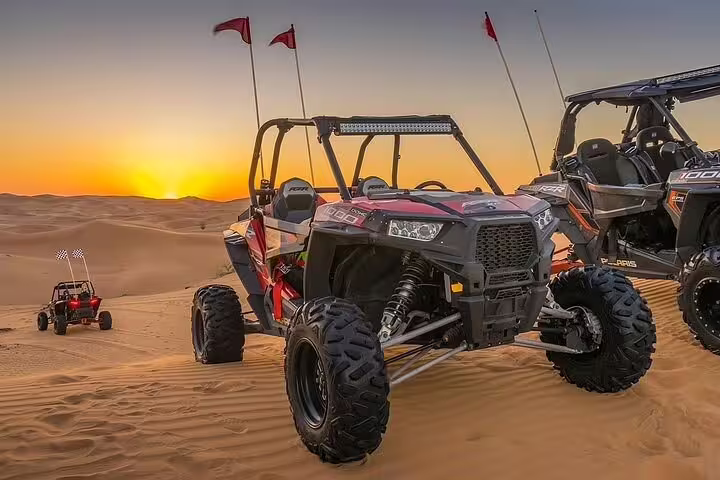 Dune buggies parked on Dubai desert at sunset, ready for an exhilarating off-road tour with stunning scenery.