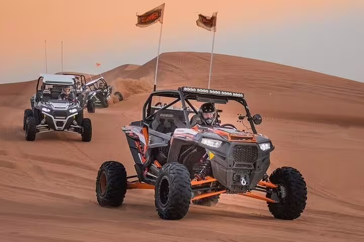 Group of dune buggies racing across the stunning Dubai desert at sunset, ideal for an exhilarating experience.