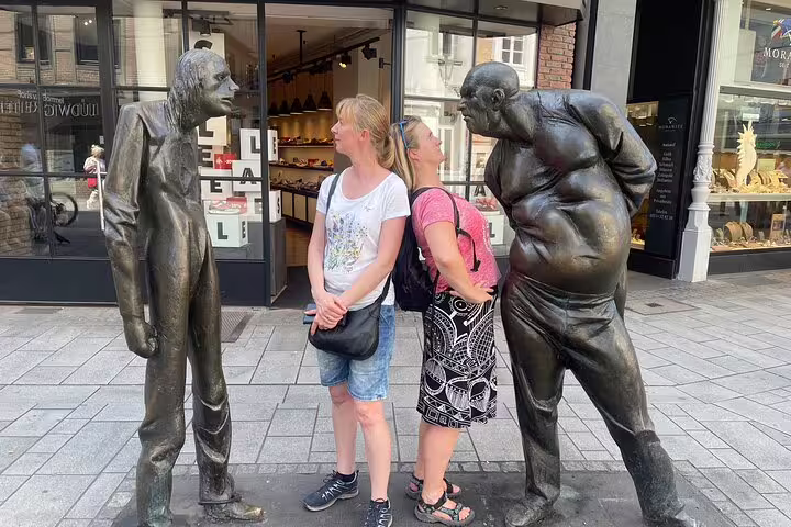 Tourists posing with Düsseldorf Altstadt street statues on a self-guided scavenger hunt walking tour